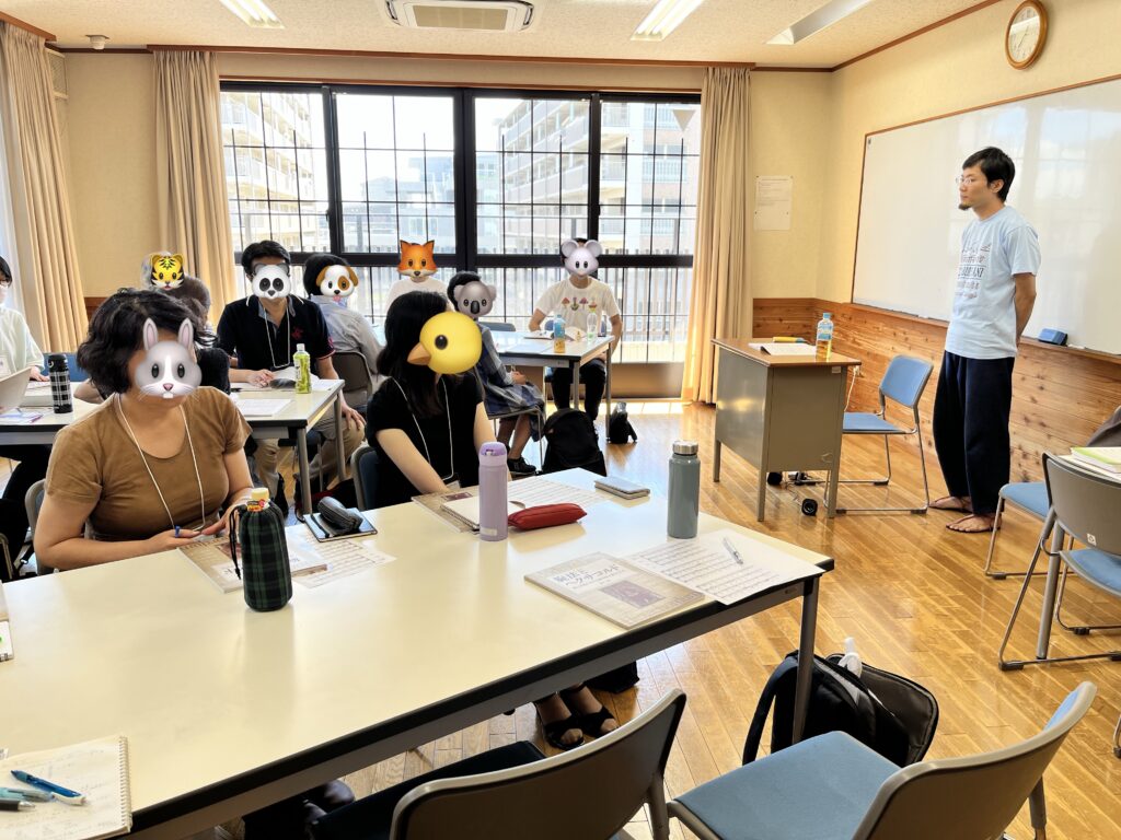第一回ワークショップの様子。正面に講師の櫻井さんが立ち、説明を参加者が長机に座って聞いている。